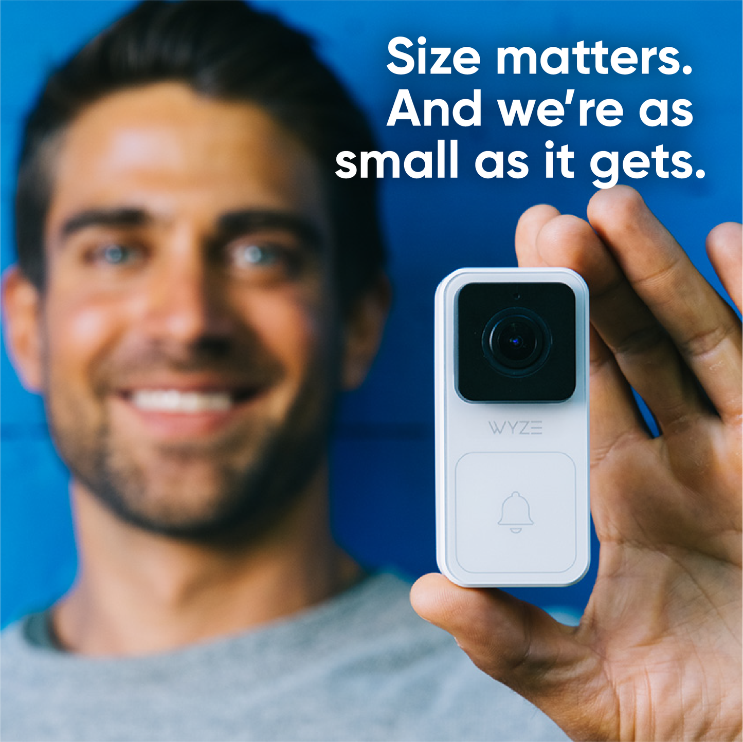 Man holding a small Wyze Video Doorbell unit between his thumb and middle fingers to show the compact size.